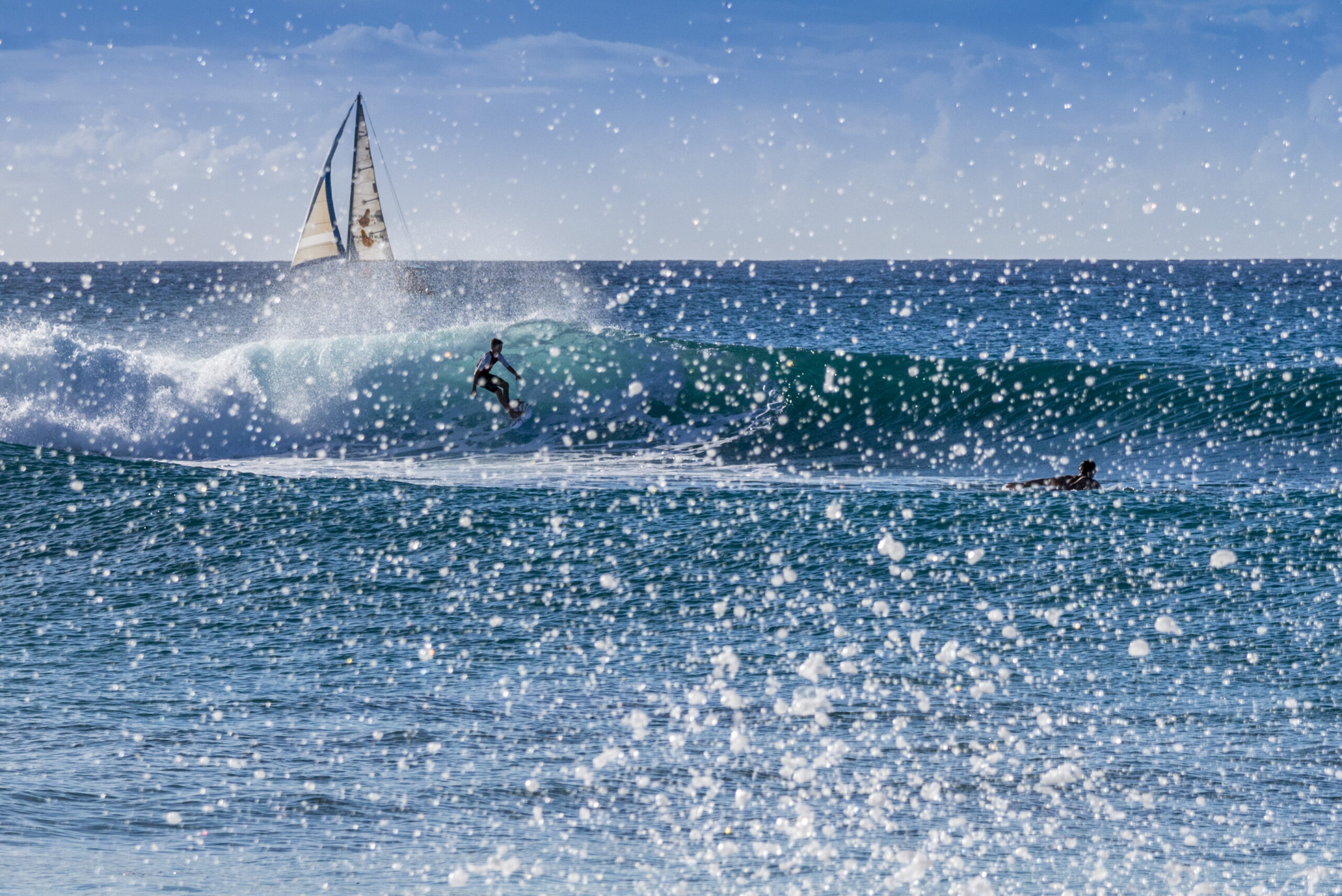 A surfer riding a wave at Reeds Bay on the Caribbean west coast of the island of Barbados in the West indies.