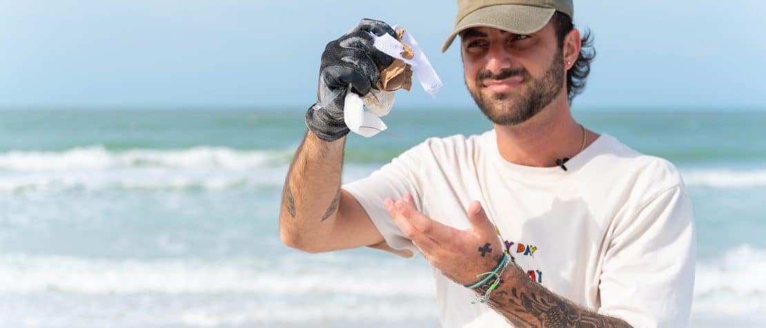 Caulin Donaldson holding up trash at beach cleanup in florida