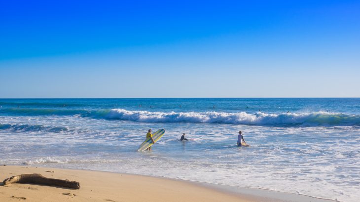 Outdoor view of surfers on the beach of Santa Teresa in a beautiful sunny day with blue sky and blue water in Costa Rica.